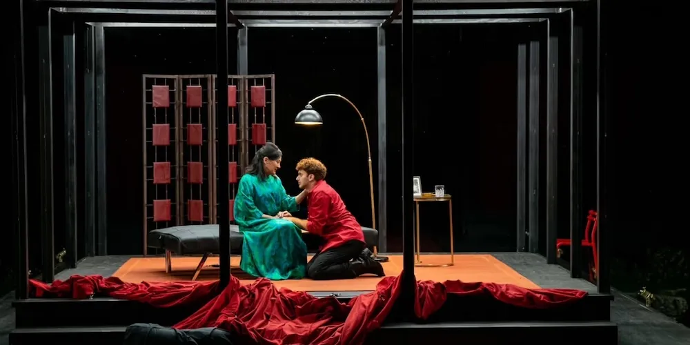 A man and woman on a stage made to look like a living room. 