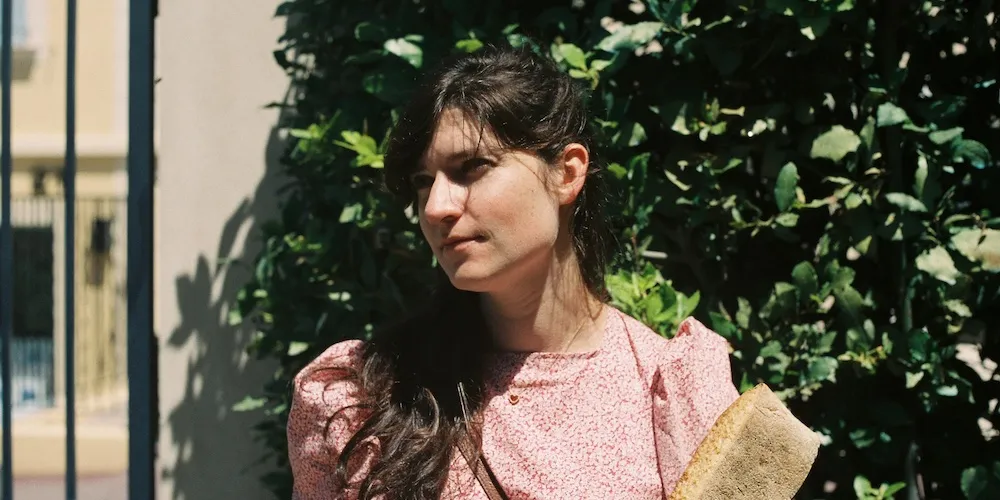 Headshot of Liba Vaynberg standing in front of greenery. 