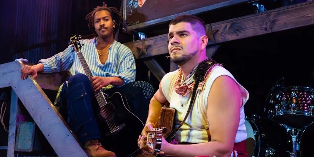 two performers on stage with guitars
