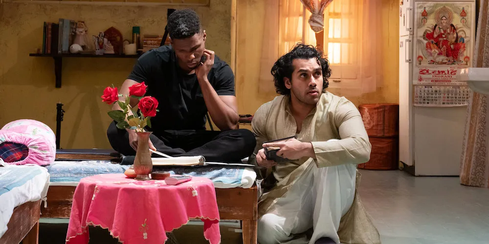 Two men on a stage designed to look like a small apartment