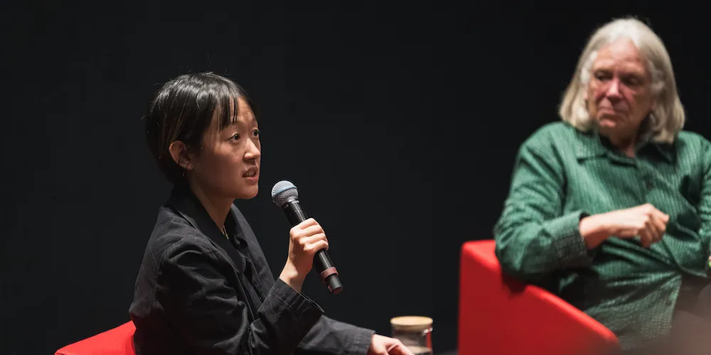 Celine Song holds microphone and speaks. 