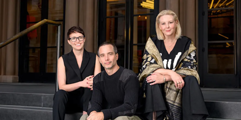 Three people sit on steps of a building. 