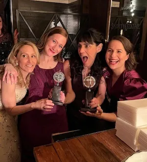 Four women holding awards. 