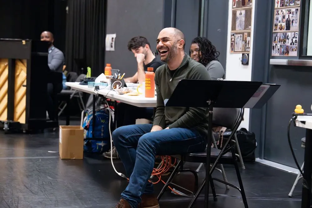 A man, sitting at a table, laughs