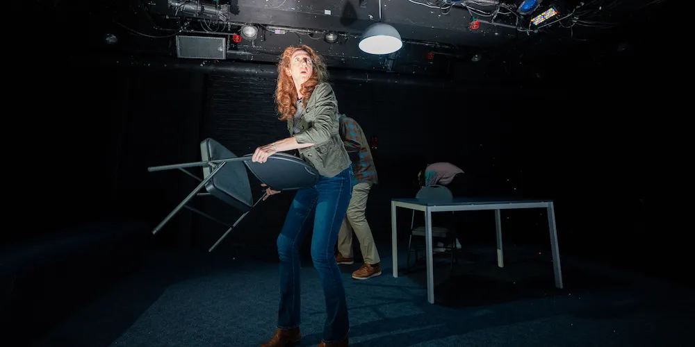 an actor wields a folding chair on stage