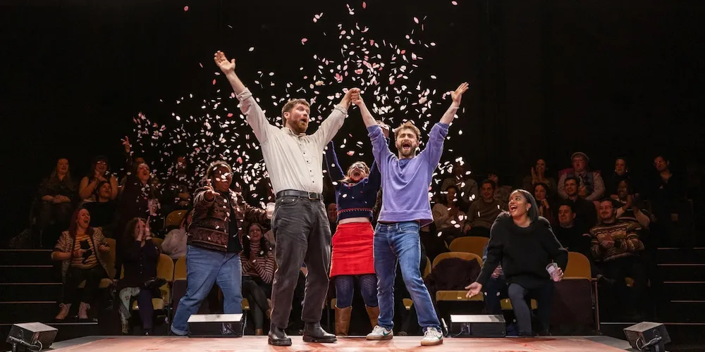 People cheer on stage as confetti falls. 
