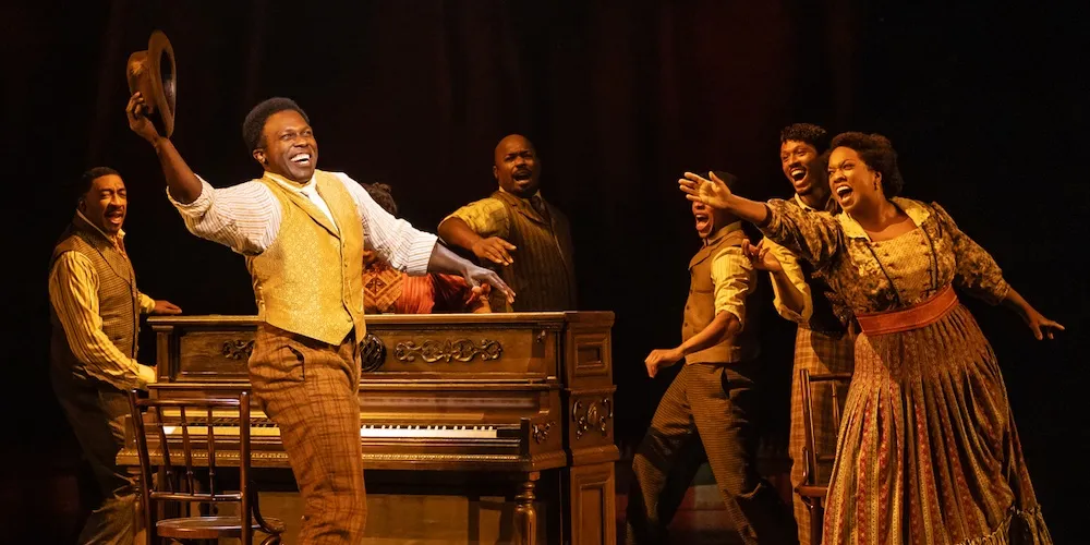 Actors sing joyfully on stage. 