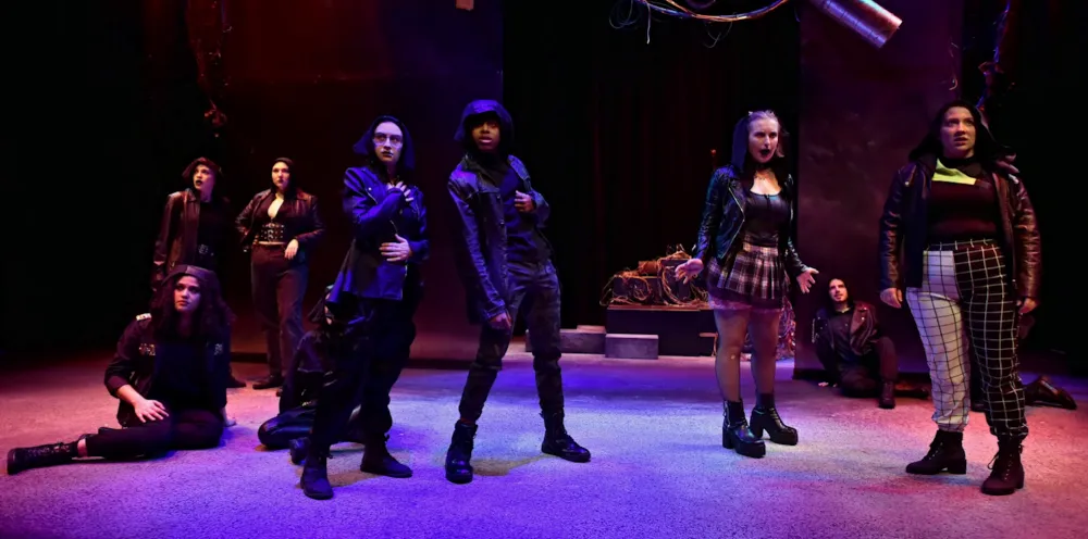 cast of characters on stage under blue spot lights