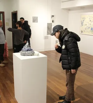 People look at art on display in a gallery