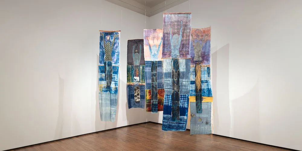Adama Delphine Fawundu '18, 'For Mama Adama Hymns, and Parables Cyanotypes,' (photo lumens on guinea brocade, cotton paper and cotton fabric, hair, raffia, water sachets, herbs, cowrie shells, acrylic paint, oil sticks, copper threads and pieces, 2022)