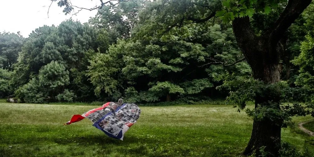 figure with quilt in field near woods