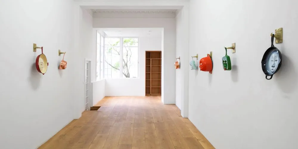 Hallway of sculptures of cookware with faces on them