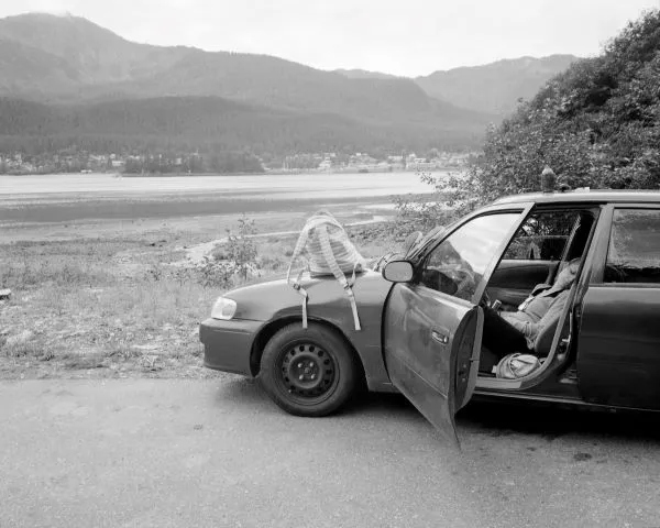 woman asleep in a car in front of an open area