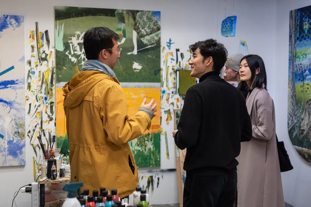 Several people in a studio space full of paintings