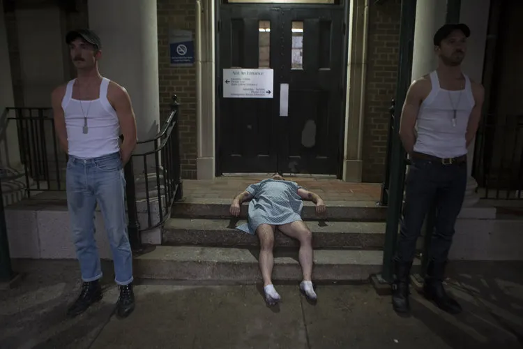 Person lying down on stairs, two others standing on either side