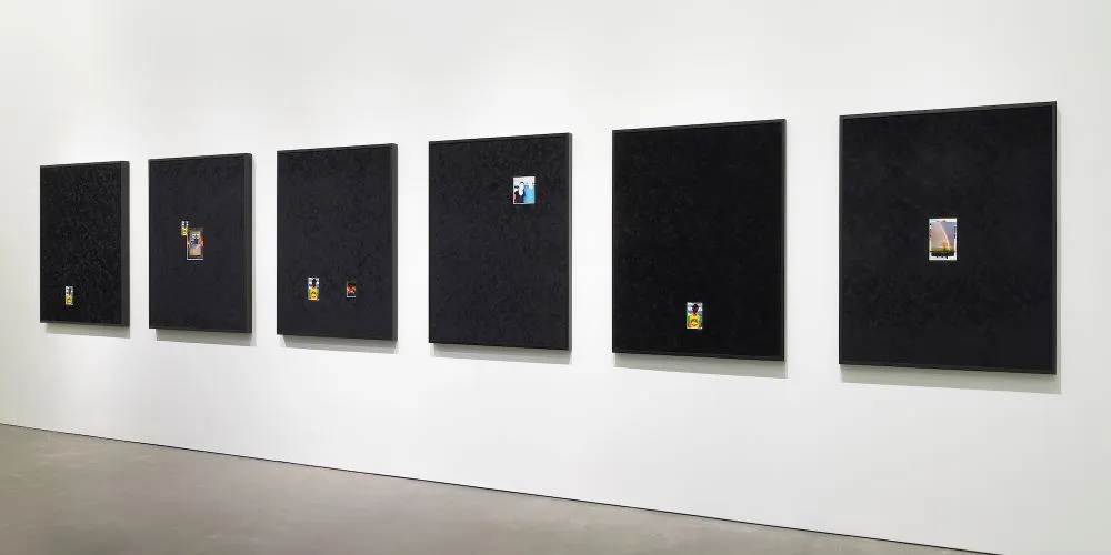 small photographs on large black canvas in a gallery