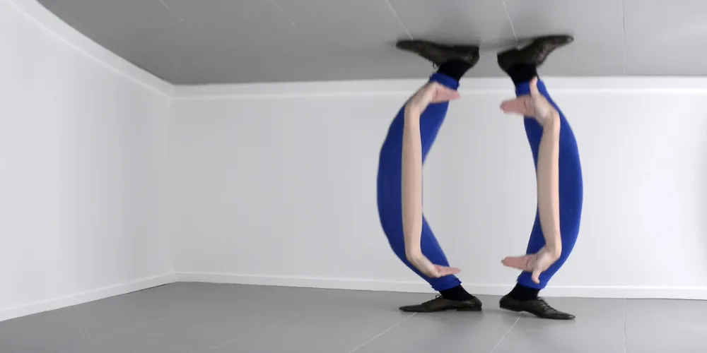 still from video art piece featuring a reflection of a pair of legs and arms