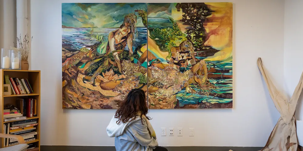A woman kneels in front of a large painting