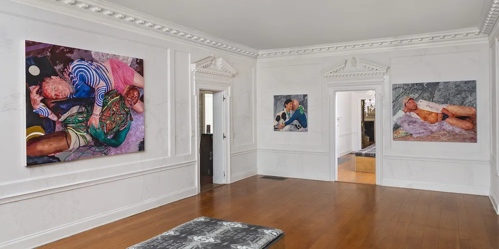 Paintings hang in a gallery. 