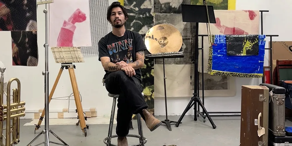 an artist sits for a photo in an art studio