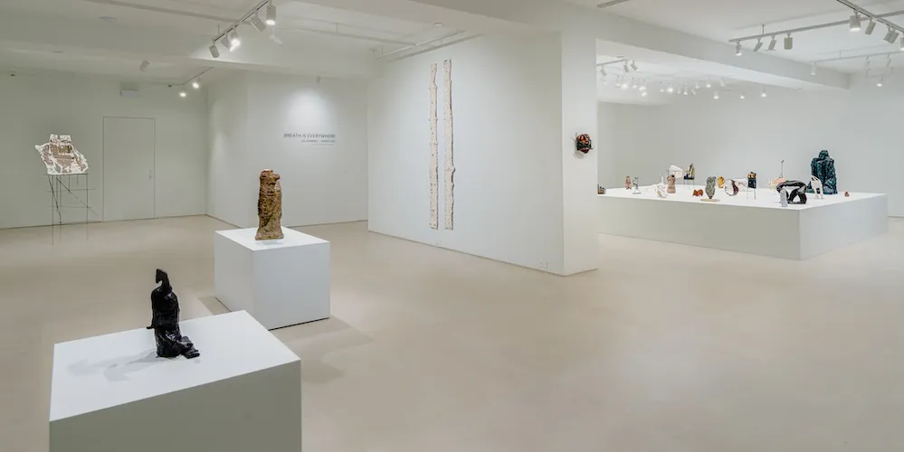 Bright white wall gallery space with sculptures on pedestals. 