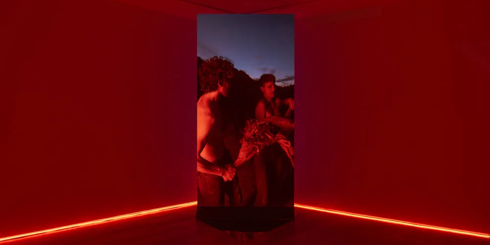 Red room with vertical screen of two people running in the corner. 