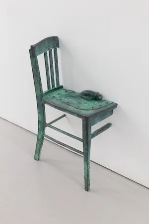 Half of a chair connects to a white wall. 