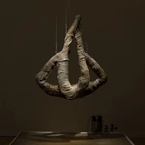 A sculpture resembling limbs hangs from a gallery ceiling. 