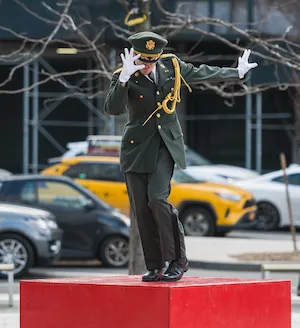 a performer wearing a uniform dances on top of a red box