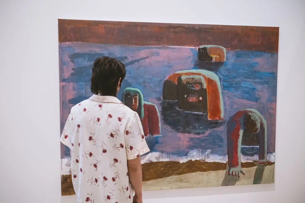 Person observes a painting on gallery wall. 