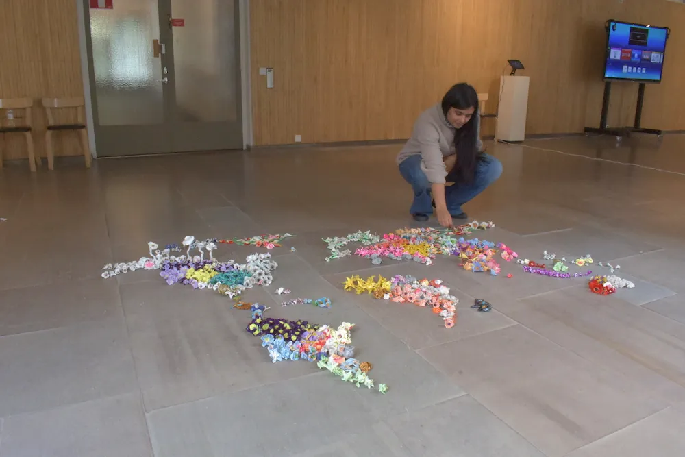 a person picks up a hand-crafted clay polymer flower from the ground in an art gallery