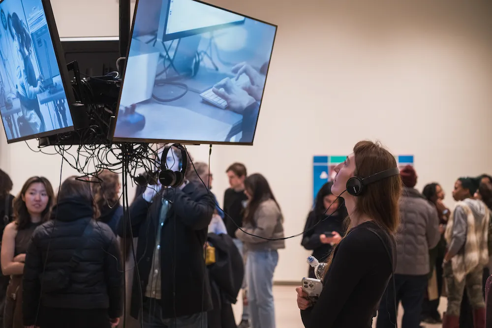 a person wearing headphones watches a video art installation