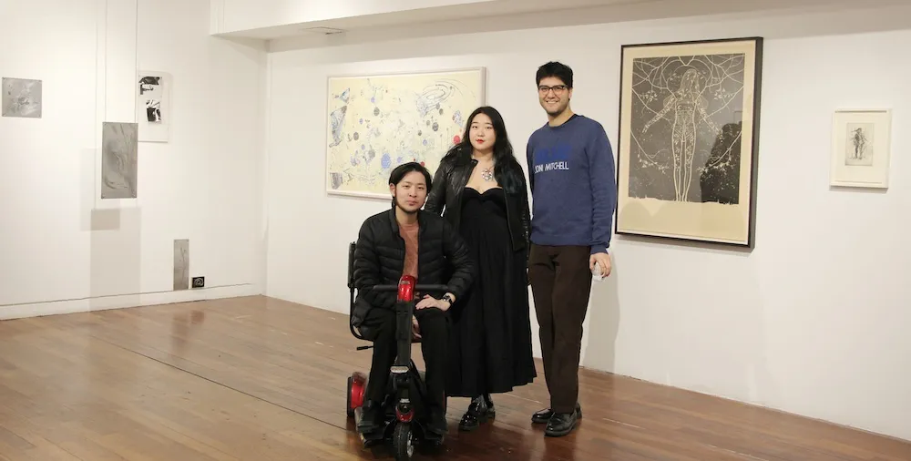three people pose for a photo in an art gallery