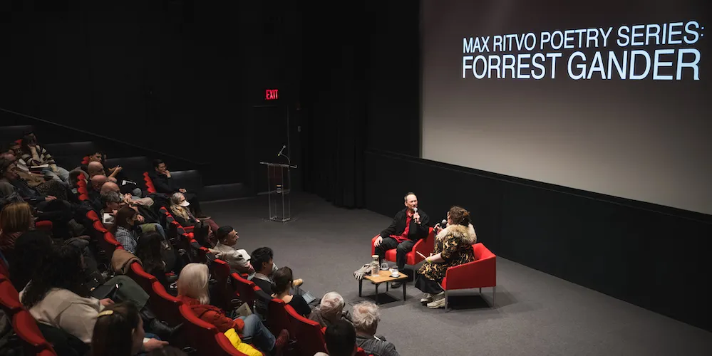 two people have a discussion in front of an audience in a lecture room