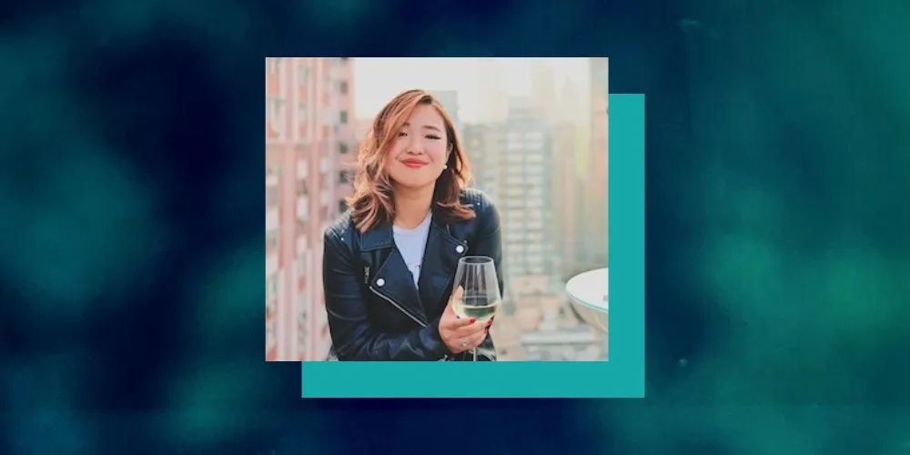 Picture of Jemimah Wei drinking a glass of white wine on a rooftop bar. 