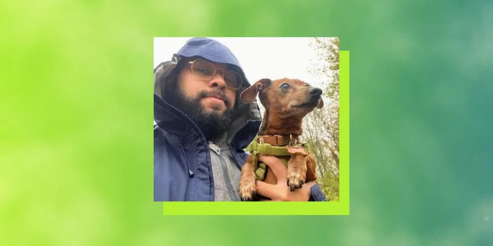 Close-up of a man and a small dog in front of a green background