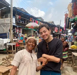 Young man with woman in white headband and white embroidered shirt in standing market. 