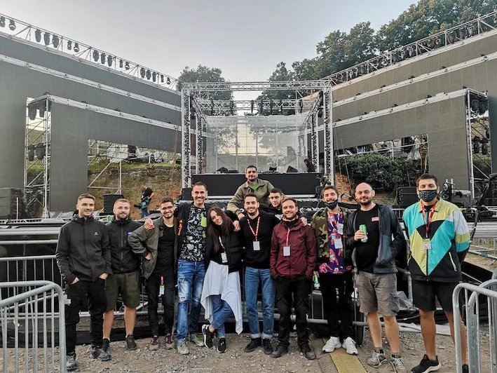 The crew gathering together for a picture outside by a stage