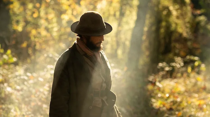 A man standing in the sunlight of a forest