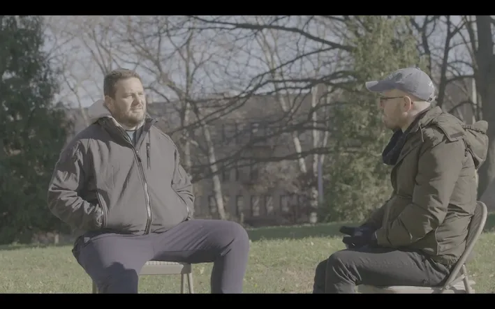 Men talking in a park, by a bench