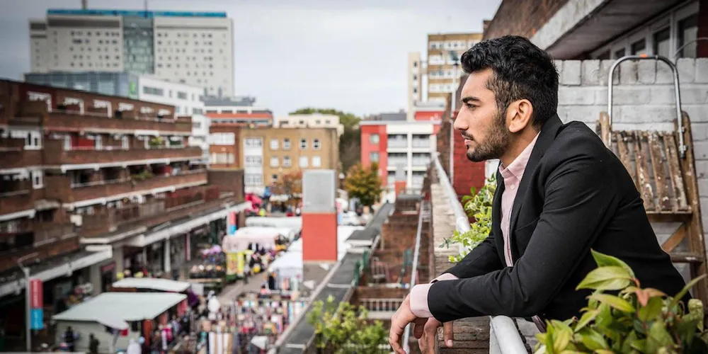 Man looking out at a city from his balcony. 