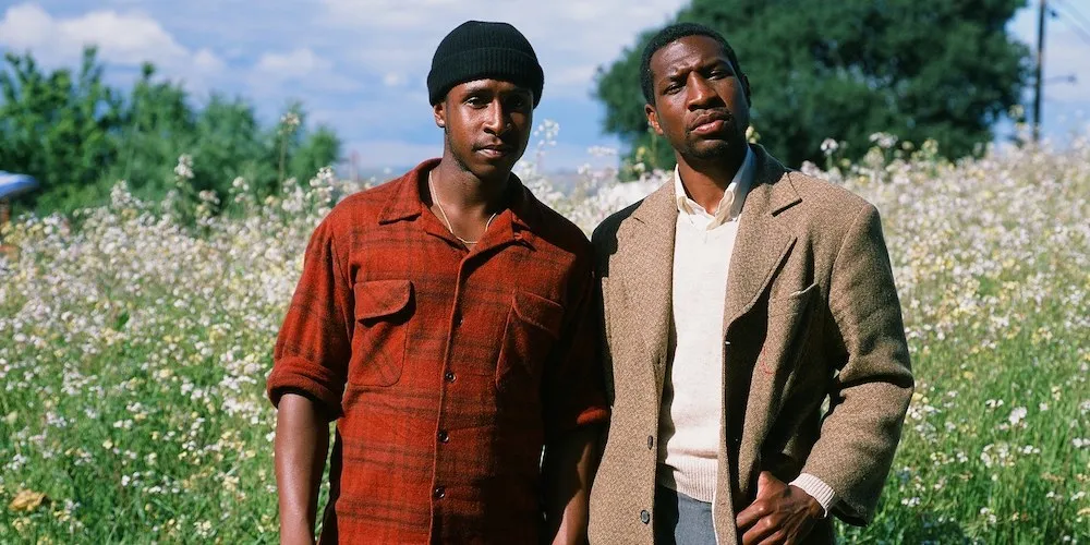 Two Black men standing in a field looking pensive
