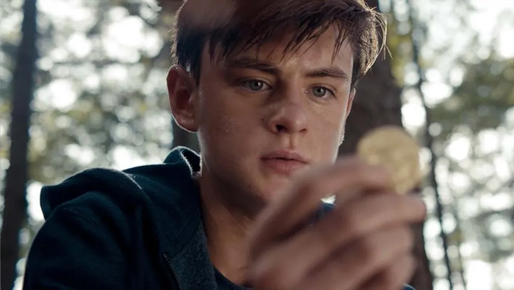 Photo from the film of a young white man looking at something in his hand. 