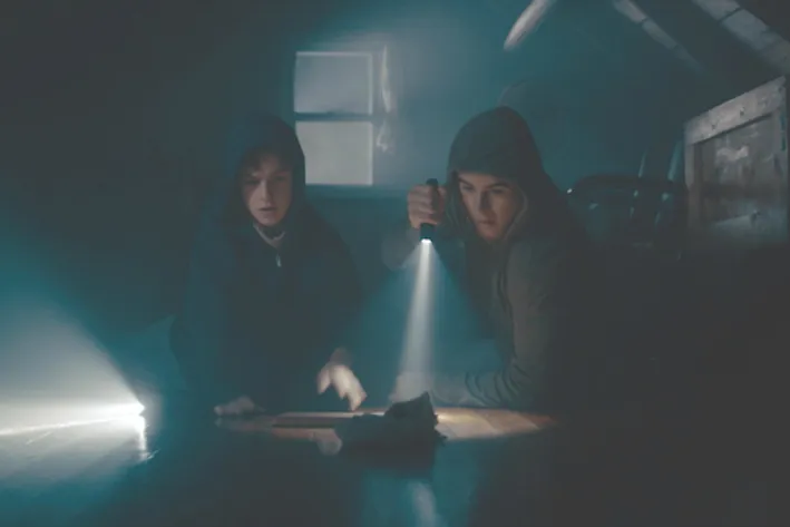Boys searching a dark space with a flashlight 