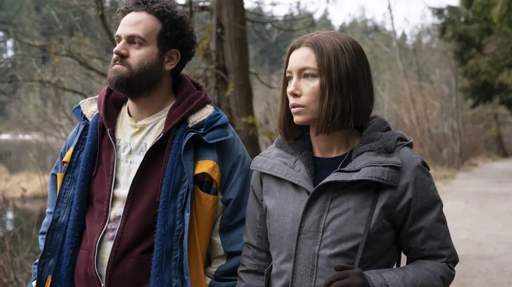 A white man and woman walking through the woods. 