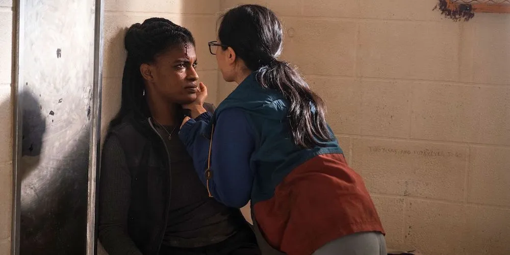 A movie scene where a wounded woman looks up at another one.