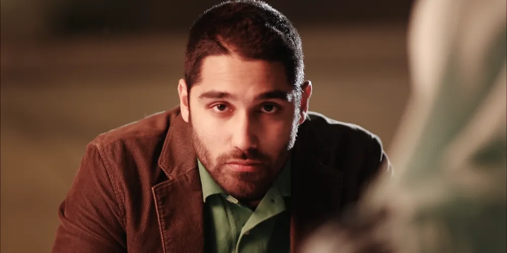 A man with a shaved head staring into the screen. 