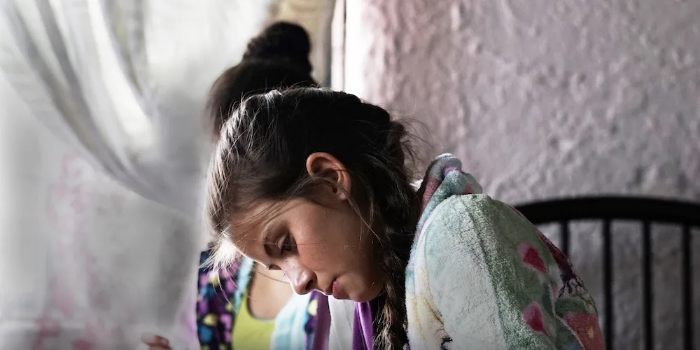 A brunette girl with a braid looking down. 