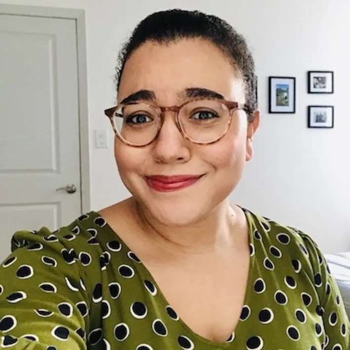 Woman with glasses and a green shirt smiling