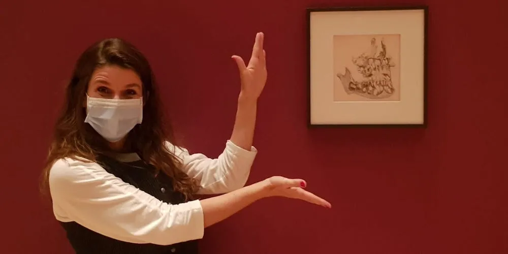 White woman with brown hair showing her art.